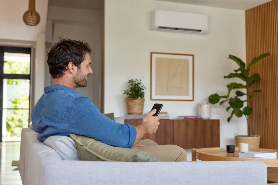 Homeowner controlling a Midea split system from a smartphone in a Melbourne living room